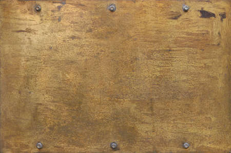 rusty golden metal surface with yellow and orange tones - worn steampunk background with screws and scratchesの写真素材