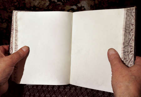 hands of a mature man holding a big open blank book of literature - reading text