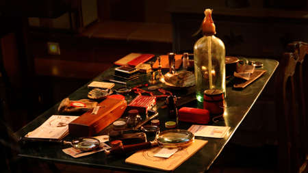 Old objects and antiquarian tools such as bottles, hourglasses, pots, magnifying glasses and other hookahs of a cabinet- Warm omposition on a dark backgroundのeditorial素材