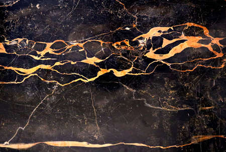 black marble surface with yellow and orange organic shapes like rays - abstract textured background wallpaperの写真素材