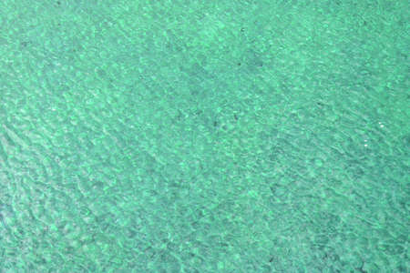 turquoise blue water of a swimming pool with little waves texture - warm background pattern with the...