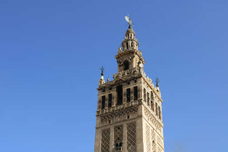 the top of Giralda tower in Seville isolated with a clean blue sky in the background for a wallpaperの写真素材