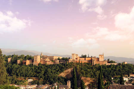 colorful landscape of Granada city at sunset, with the Alhambra in the background, mountains, trees...