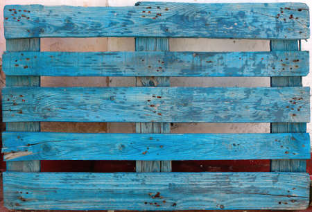 Decorative recycled light blue pallet with peeling painting on an outdoors wall