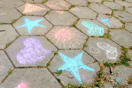 children's drawings of hearts, stars and sun with colored chalk on the street salary with hexagonal tiles together as in a beehiveの写真素材
