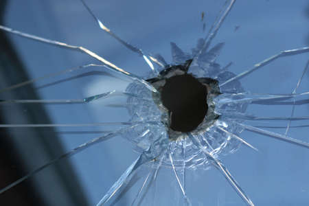 broken glass cracked with a hole from a stone or a bullet in the surface - closeupの写真素材