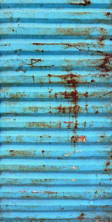old wavy metal door gate of a garage painted in blue color, damaged and scratched - vertical weathered background with horizontal linesの写真素材