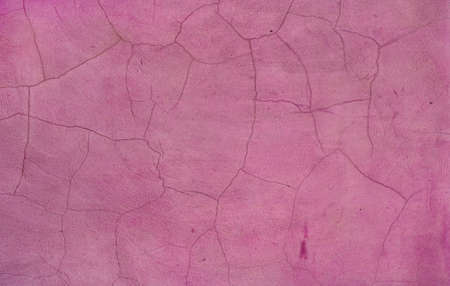 old cracked pink wall - weathered and damaged surface texture from a facade backgroundの写真素材