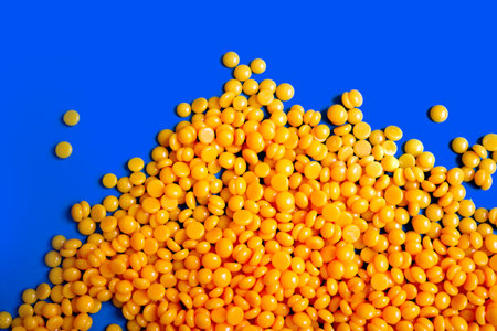 pile of hard wax beans over a blue chroma key background representing orange lentils or corn seedsの写真素材