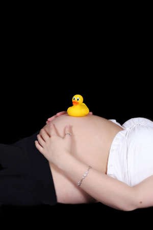 colourful toy duck resting on top of beautiful bare pregnant belly. isolatedの写真素材