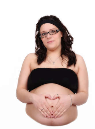 beautiful pregnant woman making heart shape with hands on bare tummy. isolatedの写真素材