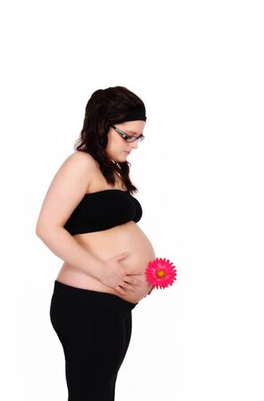 beautiful pregnant woman holding flower looking down at bare belly. isolatedの写真素材