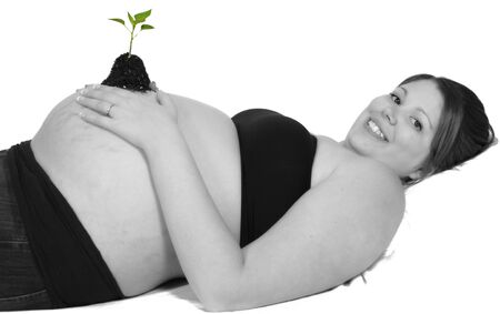 pregnant woman laying with tiny seedling resting on bare belly. selective. isolated on whiteの写真素材