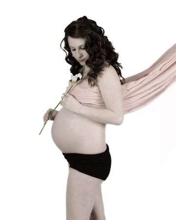 young pregnant woman with drape covering breasts as she admires a calla lily. isolated on whiteの写真素材