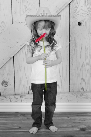 adorable cowgirl smelling flower in selective colorの写真素材
