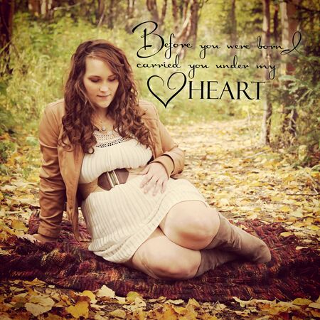 beautiful of pregnant woman sitting on forest path in fall with typographyの写真素材
