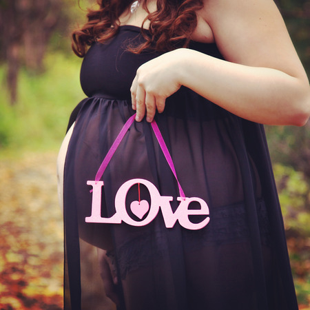 beautiful of pregnant woman holding quote forest path in fallの写真素材