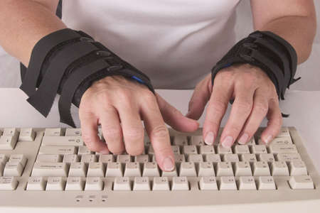 woman's hands in wrist braces typingの写真素材