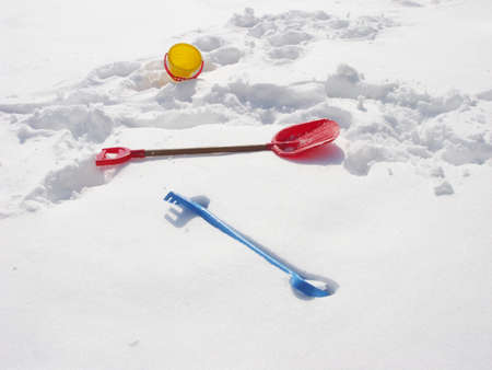 Toy bucket, rake and spade with snow isolated on white background/ Winter/ Horizontal. Colored children's toys in the snow. Bucket, rake and shovel which are filled up with snow, covered snow.の写真素材