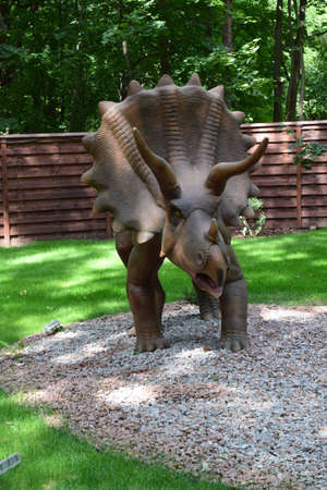 DINO PARK, KHARKOV - AUGUST 8, 2021: Dino Park Triceratops huge dinosaur of Jurassic era walks in the forest in summer on a sunny day. A wild lizard grazes in dino park for children. life of predatorのeditorial素材