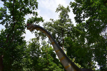 DINO PARK, KHARKOV - AUGUST 8, 2021: View of beautiful Dinosaur sculpture display in the park. Brachiosaurus realistic model. head close to dinosaur. Big model of prehistoric dinosaur Brachiosaurusのeditorial素材