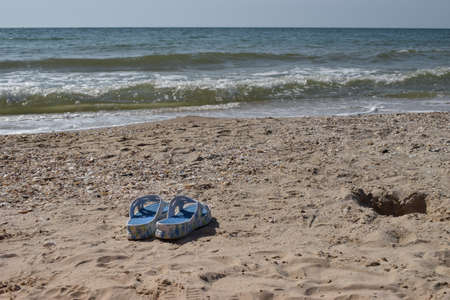 beautiful beach. Blue Beach sandals on the sandy coast. Summer holiday and vacation concept. Pair of blue flip flops on sand beachの写真素材