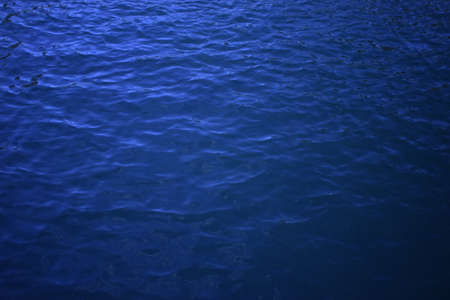 Dark blue wavy water surface. Swimming pool water texture. Blue liquid reflections. Still rippled...