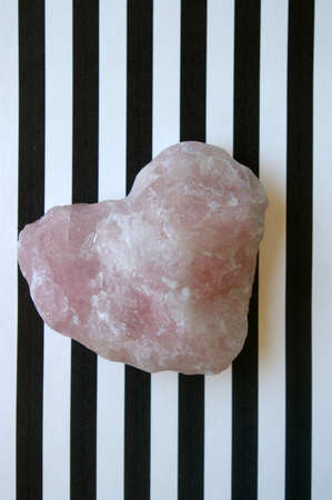 Pink gemstone heart on striped background close up
