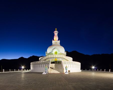 Front view of Shanti Stupa with background of twilight sky and silhouette mountain range.の写真素材