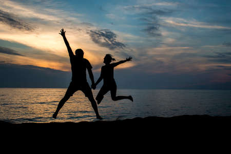 Enamoured couple jumping on beach at sunset San Vincenzo Livornoの写真素材