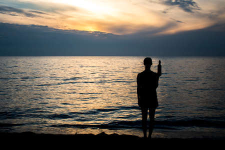 Photo (no illustration) of a girl drinking wine out of the bottle at the beach during sunset 2の写真素材