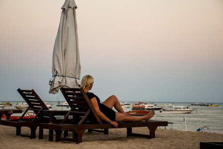 Bali in Indonesia girl sitting at Sanur Beach sunsetの写真素材