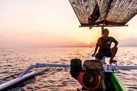 Indonesia Bali 10.10.2015 Native bali men wooden boat sunrise oceanのeditorial素材
