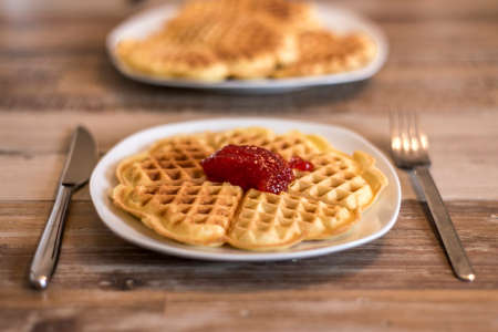 Eating Homemade waffles on white plate with red strawberry jam jellyの写真素材