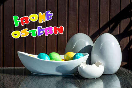 Set colorful shiny Easter eggs and grey and white colored ceramic with text happy easter in german