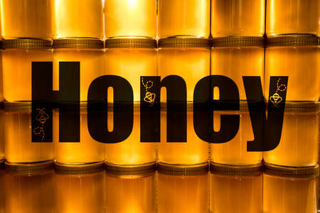 Golden yellow honey in glass jar on wooden board Closeup Copy space with textspaceの写真素材