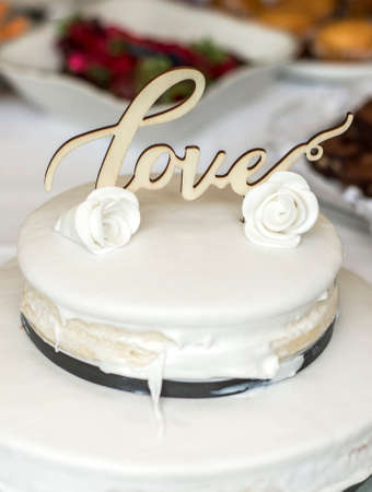 Beautiful wedding cake with cream With text Love on top and pink flowers rosesの写真素材