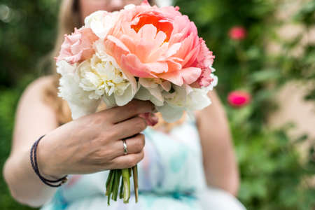 Wedding bouquet of flowers held by a bride closeup. Pink flower showing ringの写真素材