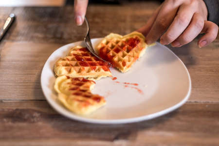 Eating Homemade waffles on a white plate with red strawberry jam jellyの写真素材