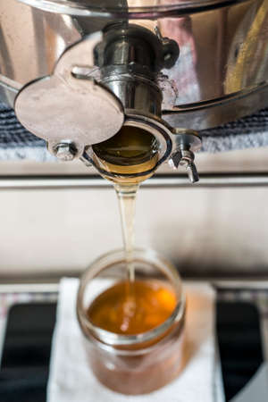Beekeeper filling up the fresh new honey into glass jars on a scale scalesの写真素材