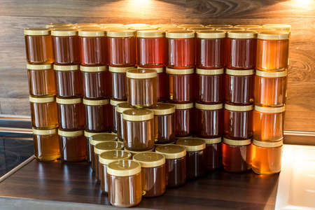 Golden yellow honey in glass jar on wooden board Closeup Copy spaceの写真素材