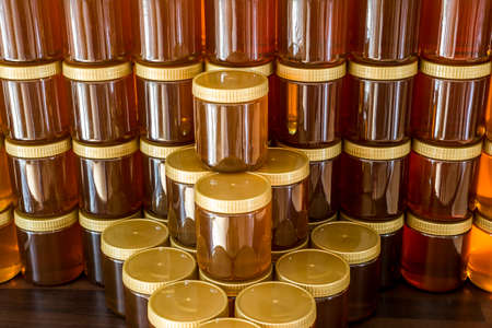 Golden yellow honey in glass jar on wooden board Closeup Copy spaceの写真素材