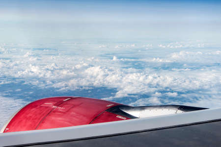 red jet engine turbine look through aircraft window on sunny day blue sky clouds