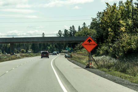 Canada Ontario 09.09.2017 Orange construction worker sign at road into the distance on trans canadaのeditorial素材