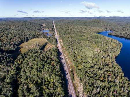 Canada beautiful scenic camper bus driving on road in the endless pine tree forest with lakes moor land , aerial view travel backgroundの写真素材