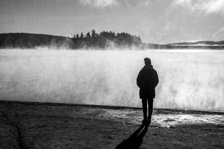 Beautiful woman standing lake of two rivers algonquin national park Canada look sunrise mist in the fog clouded swampの写真素材