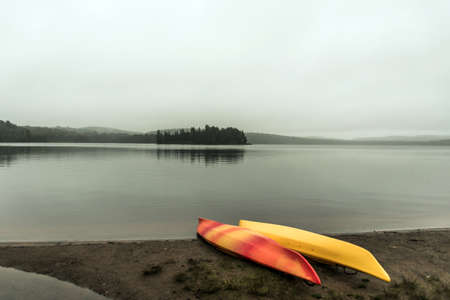 Canada Ontario Lake two rivers grey morning dark atmosphere Canoe Canoes parked beach water in Algonquin National Parkの写真素材