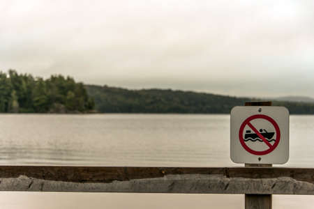 Canada Ontario Lake two rivers grey morning dark atmosphere sign beach no motor boats allowed in Algonquin National Parkの写真素材