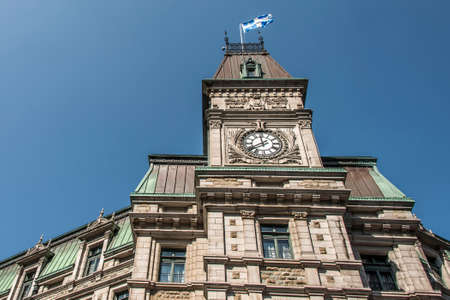 Classic clocktower building Quebec City Canada with flag of quebec on a sunny day blue skyの写真素材
