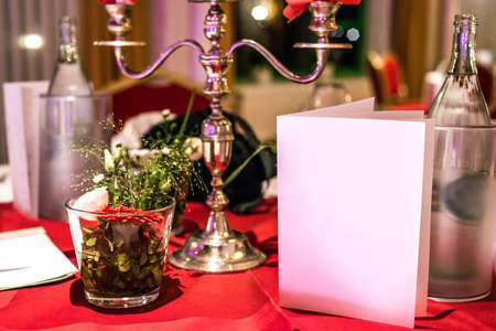 Banquet with red table setting tablecloth white dishes silver cutlery glasses and decorations white copy text space cardの写真素材